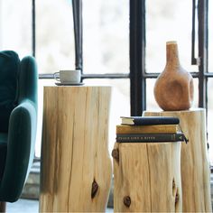 two wooden stumps with books on them in front of a window and a chair