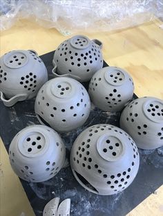 several gray ceramic pots sitting on top of a wooden table with holes in the middle