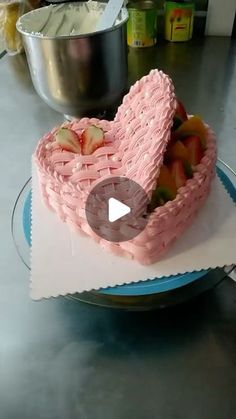 a heart shaped cake sitting on top of a table next to a bowl of fruit