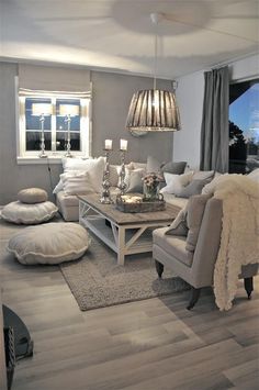 a living room filled with lots of furniture and pillows on top of a wooden floor