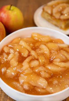 two bowls filled with apple pie on top of a wooden table next to an apple