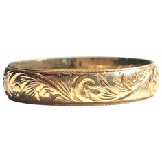 a gold wedding band with an intricate design