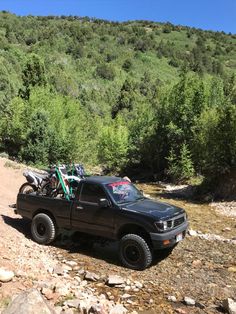 a black truck parked on top of a rocky hillside