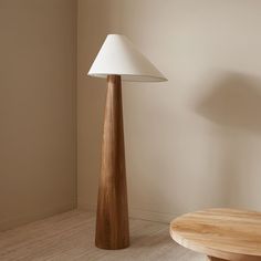 a wooden table sitting next to a white lamp on top of a hard wood floor