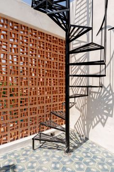 a spiral staircase in front of a wall with lattices on the sides and an iron handrail