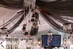 a room with chandeliers and decorations hanging from it's ceiling in front of a flat screen tv