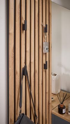 a black bag hanging on a wooden wall next to a mirror and table with other items