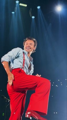 a man in red pants is dancing on stage