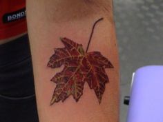 a woman's arm with a leaf tattoo on it