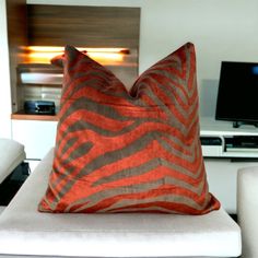 a zebra print pillow sitting on top of a white couch in front of a flat screen tv