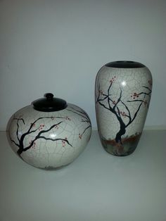 two white vases with designs on them sitting next to each other in front of a wall