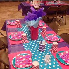 the table is set with pink and blue polka dot paper napkins, cups, and plates