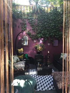 an outdoor living room with plants on the wall and black and white checkered flooring