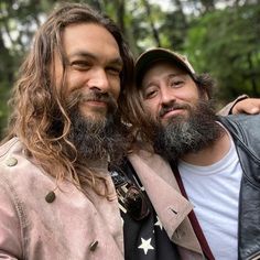 two men with long hair and beards standing next to each other