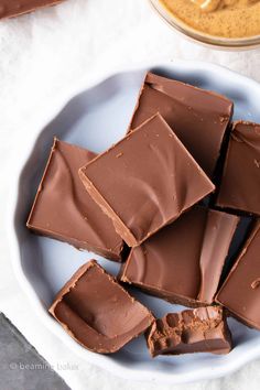 a white bowl filled with pieces of chocolate and peanut butter on top of a table