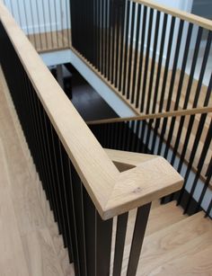 a wooden stair case with black handrails