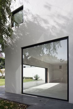 an open window on the side of a white building with trees in front of it