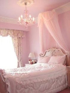 a pink bedroom with white bedding and chandelier hanging from the ceiling above it