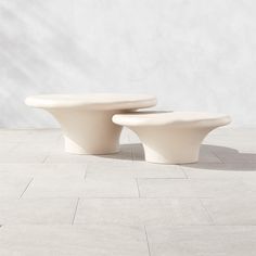 two white toilets sitting next to each other on top of a tiled floor in front of a wall