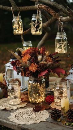 mason jars filled with flowers and candles are hanging from a twigy tree branch