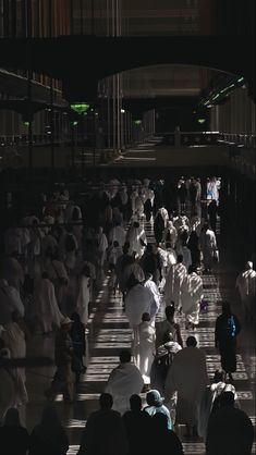 a large group of people walking down a street next to each other in the dark