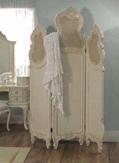 an antique white armoire and mirror in a room