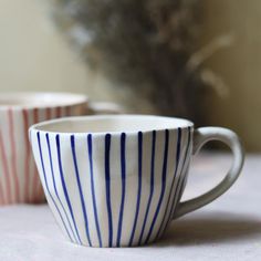 three striped coffee cups sitting on top of a white table covered in pink and blue stripes