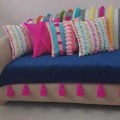 a blue couch with colorful pillows and tassels on it