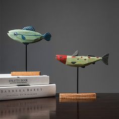 two wooden fish sculptures sitting on top of a table next to books and a book