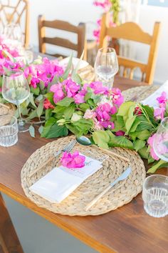 the table is set with pink flowers and place settings for guests to sit down at