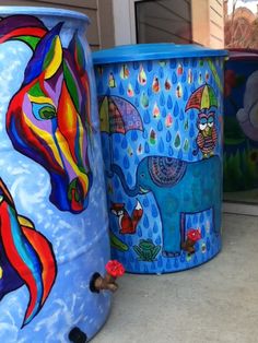 three brightly painted trash cans sitting on the ground