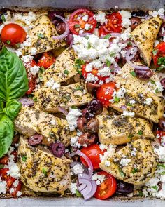 chicken, tomatoes, olives and feta cheese in a baking pan with basil leaves