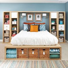 a bedroom with blue walls, white bedding and lots of storage boxes on the floor