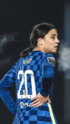 a female soccer player wearing a blue and yellow uniform with her hands on her hips