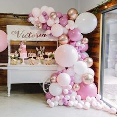 a table topped with lots of balloons next to a white cart filled with cakes and desserts