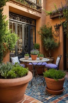 an outdoor patio with potted plants on the table and chairs in front of it