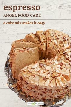 a cake with almonds on it sitting on top of a glass plate next to a wooden table