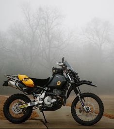 a dirt bike parked on the side of a road in front of some foggy trees