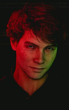 a young man with freckles on his face is looking at the camera while wearing a black shirt