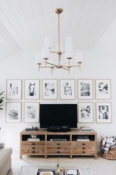 a living room with pictures on the wall and a television in the center, along with a coffee table