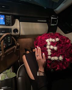 a woman sitting in the back of a car holding a bouquet of red and white roses