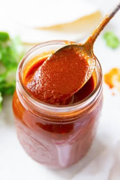 a spoon full of sauce sitting on top of a table