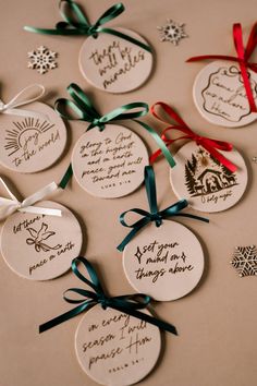 christmas ornaments are arranged on a table with ribbons and tags in the shape of snowflakes