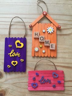 three popsicle crafts are hanging on a wooden table with the words home and love spelled across them