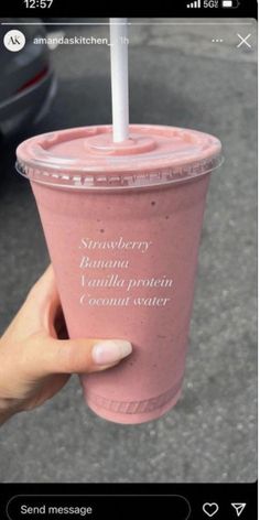 someone holding up a pink smoothie with a straw in it that says strawberry banana vanilla milkshake