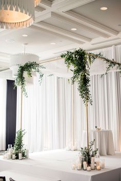 a table with candles and greenery on it in front of a curtained wall