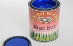 a can of blue paint sitting on top of a white table next to a black lid