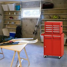 there is a red toolbox in the garage next to a table with tools on it