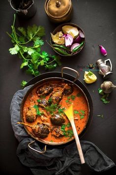 a pan filled with meat and vegetables on top of a black table next to other dishes