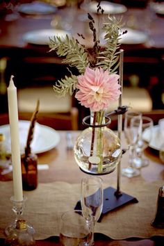 a vase with flowers is sitting on a table next to some wine glasses and candles